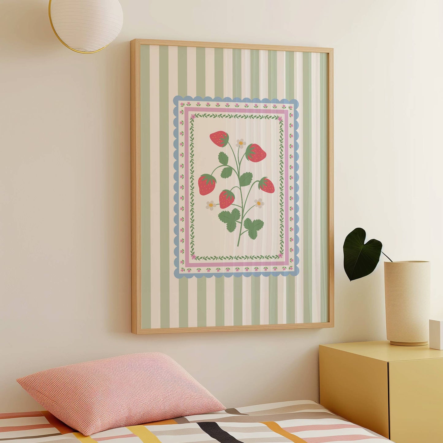Framed artwork with strawberry floral design on a wall above a bed in a bedroom.