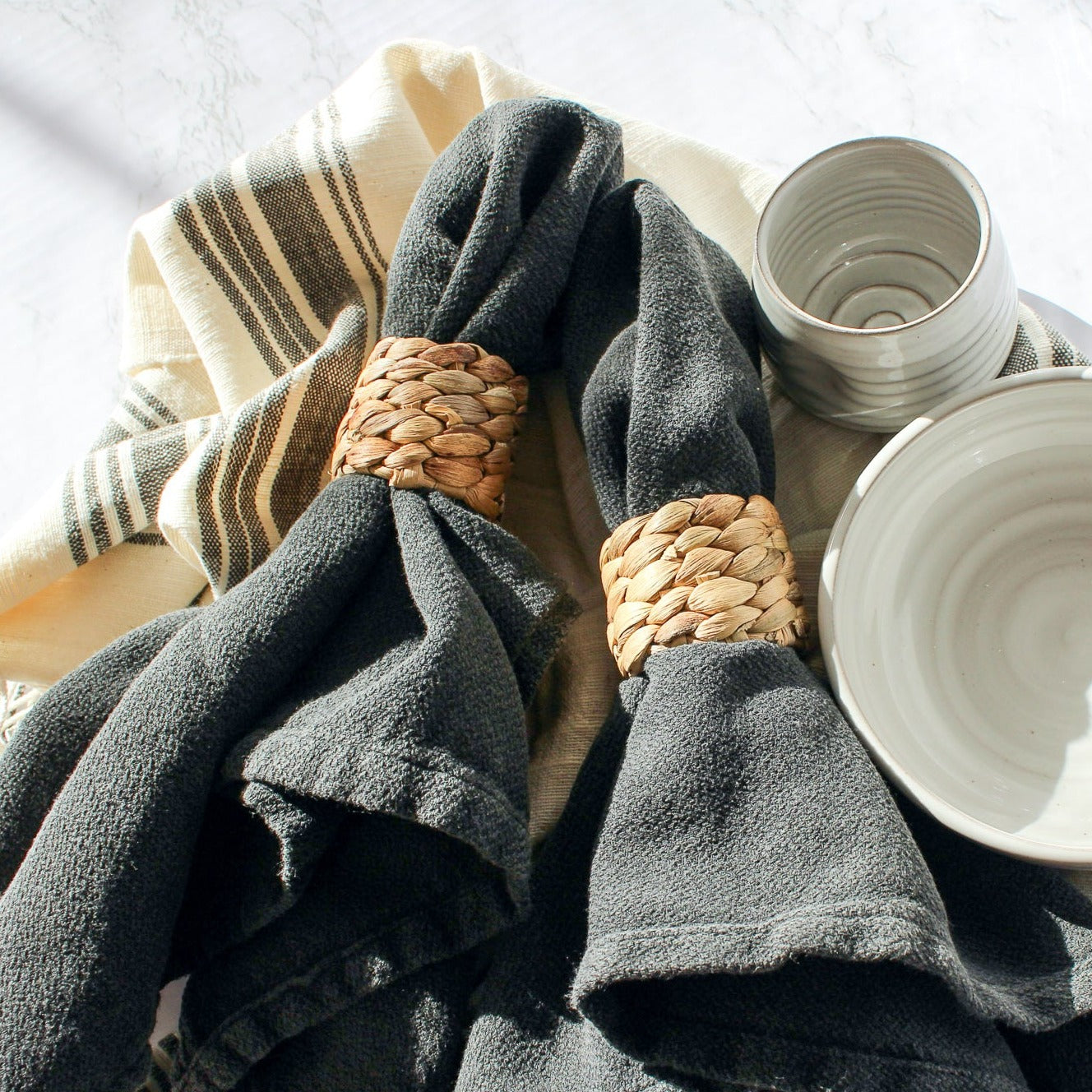 The cabin hatch hand towel, natural with grey hatch stripes, lays on the counter with our cloth napkin and seagrass napkin rings. Alongside our tipsy tumbler and favorite bowl.