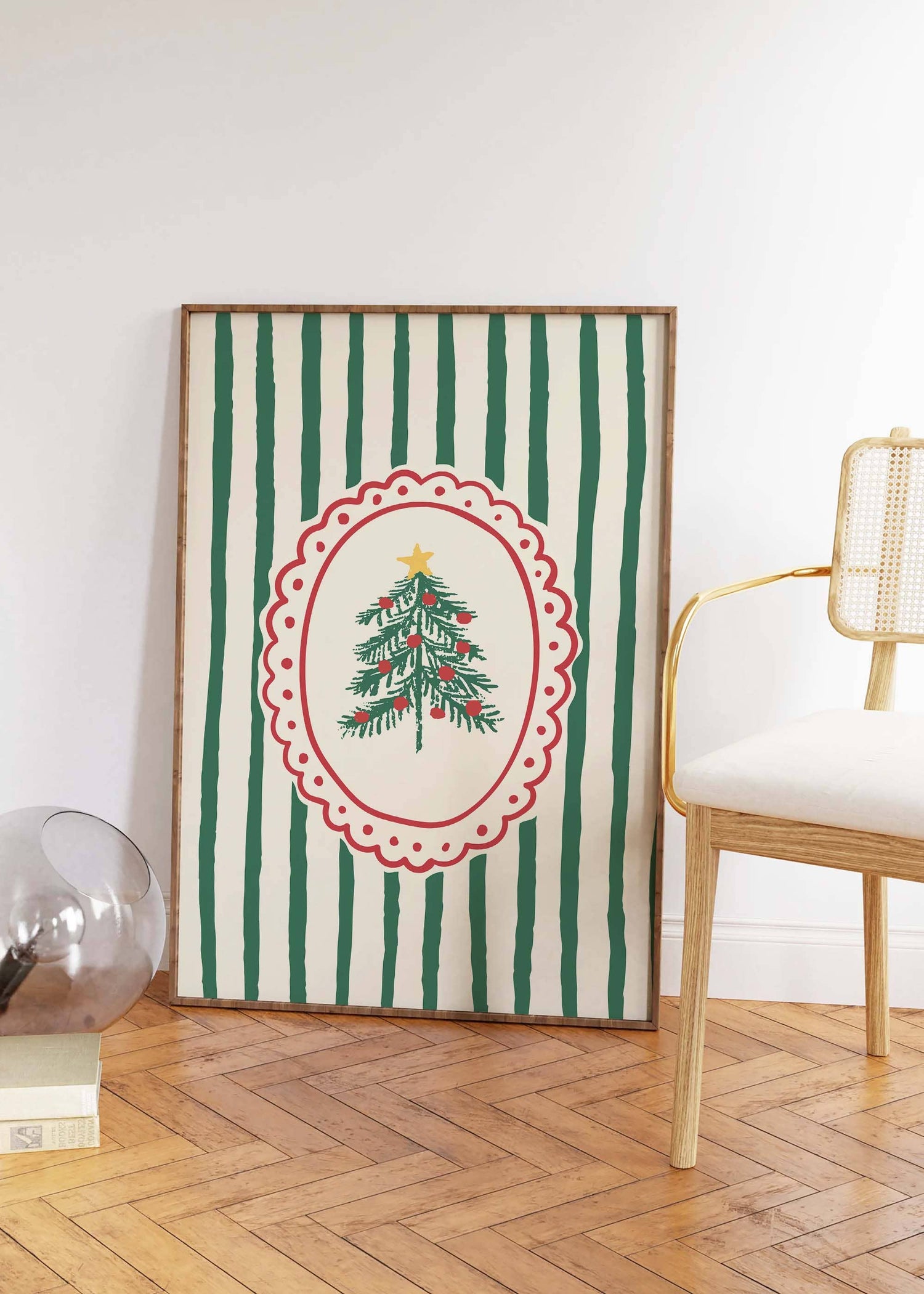 Framed artwork with a Christmas tree design on a striped background, placed on a wooden floor.
