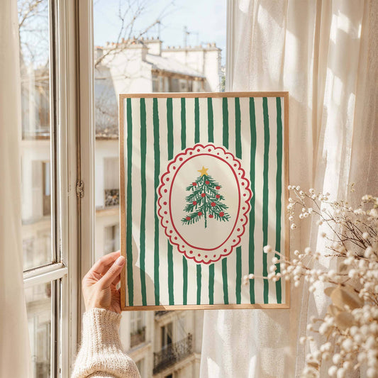 Framed artwork with a Christmas tree design held by a person in front of a window.