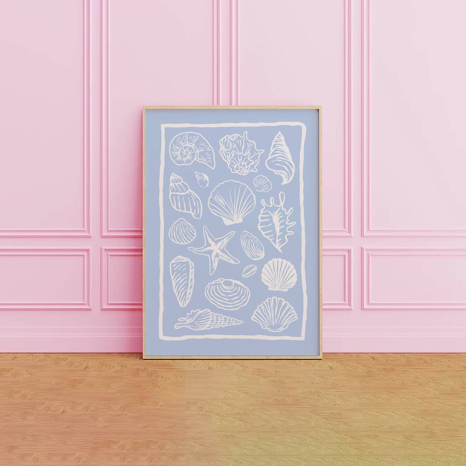 Framed artwork with white shell illustrations on a light blue background, against a pink paneled wall.