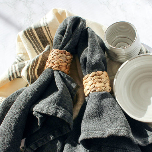 Our cloth napkins in Abyss are paired with our seagrass napkin rings. These are laying next to Our Favorite Bowl and Tipsy Tumbler.