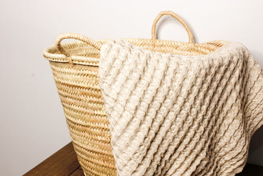 A waffle textured Turkish towel draped over the side of our French Market Tote